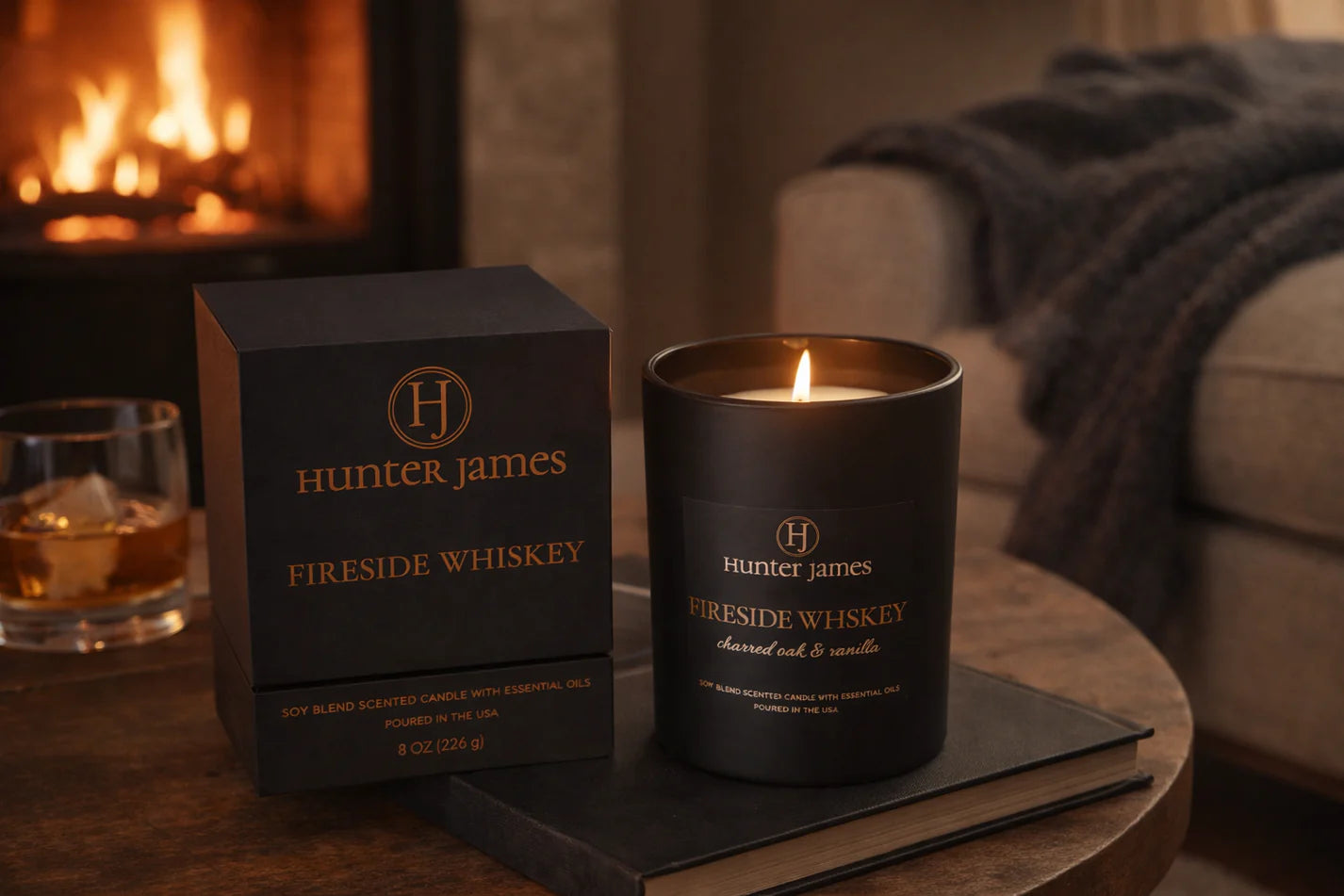 Hunter James Fireside Whiskey candle and packaging on a table with a fireplace in the background