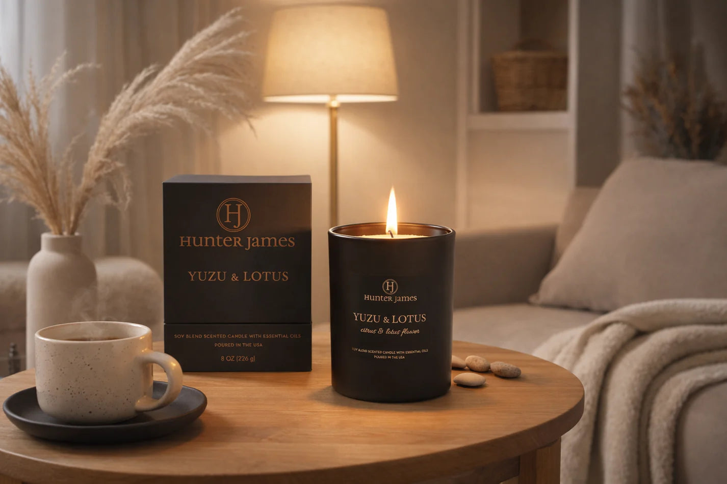 Hunter James Yuzu & Lotus candle on a table with a cup and packaging in a cozy living room.