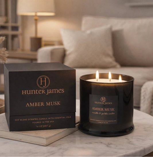 Hunter James Amber Musk candle and packaging on a marble table in a living room setting.