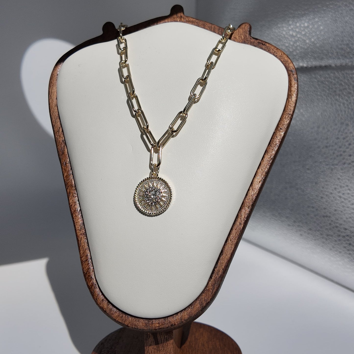 Close-up of gold sunburst medallion pendant necklace with textured vintage-inspired detailing
