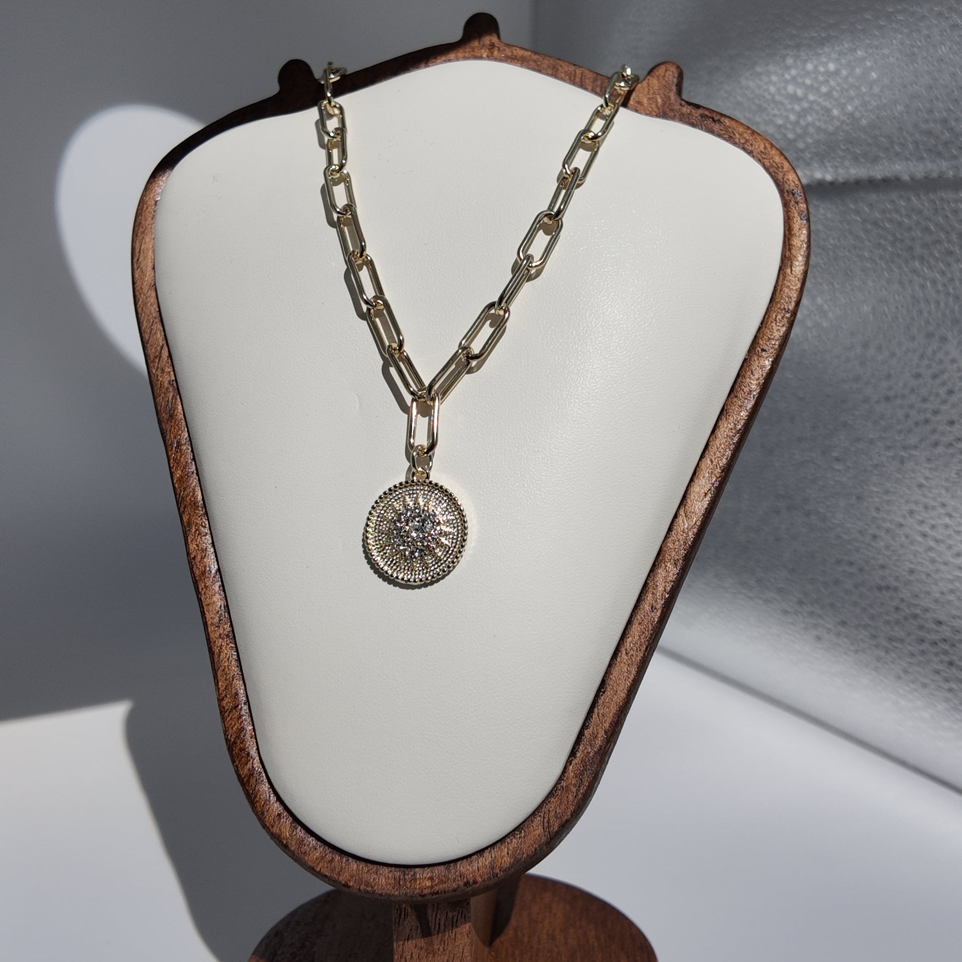 Close-up of gold sunburst medallion pendant necklace with textured vintage-inspired detailing