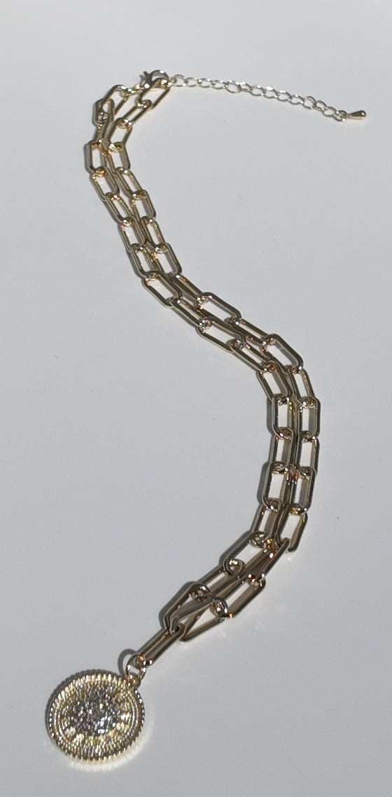 Full-length flat lay of gold sunburst medallion necklace with elongated chain styling