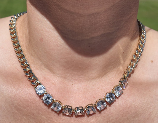 Model wearing gold crystal chain necklace featuring oversized cubic zirconia stones and chunky chain accents