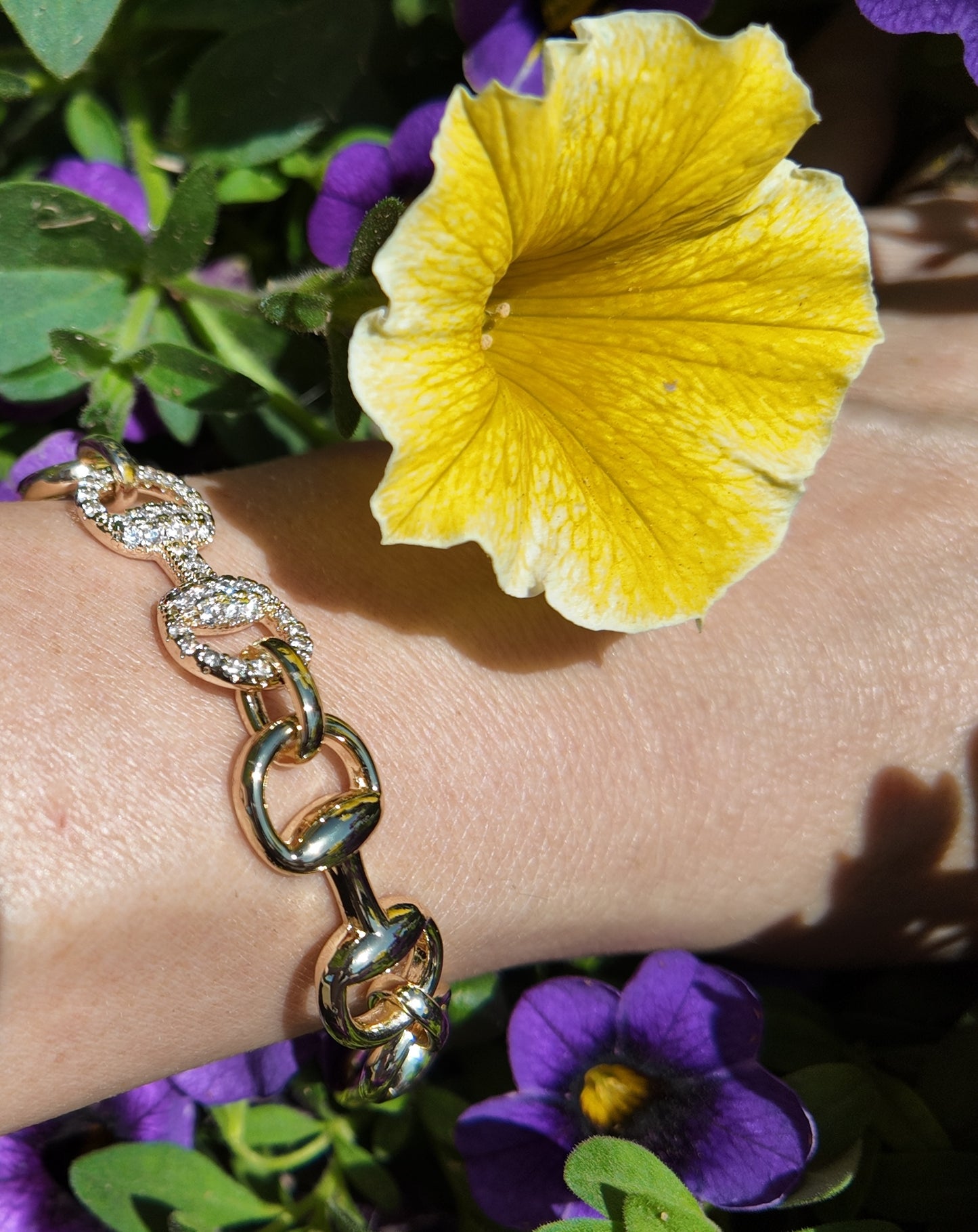     Gold Adelaide horsebit link bracelet photographed with floral accents outdoors