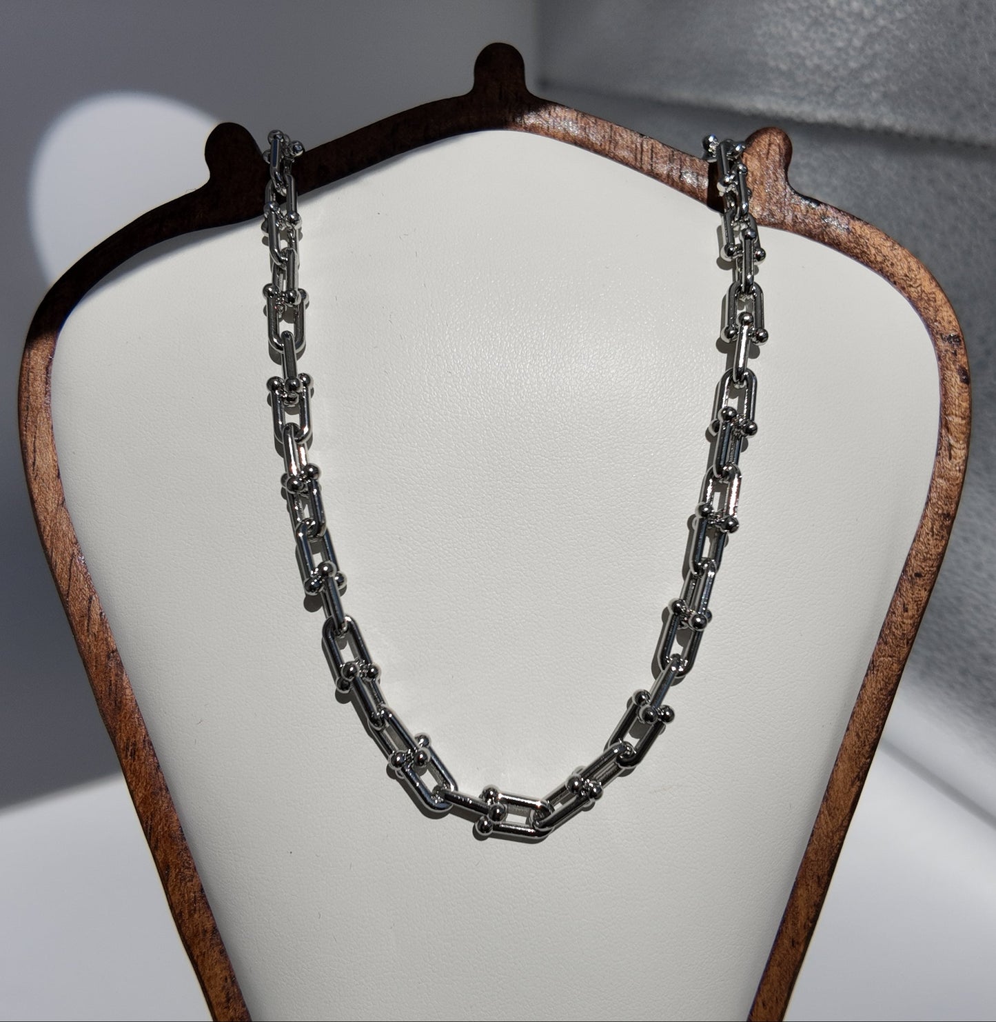 Silver Blaire paperclip chain necklace displayed on a cream jewelry stand with modern polished link detailing