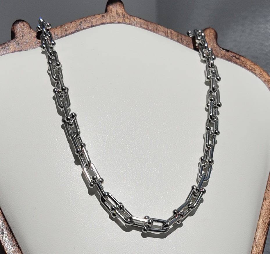 Silver Blaire paperclip chain necklace photographed in a flat lay highlighting contemporary paperclip-inspired links