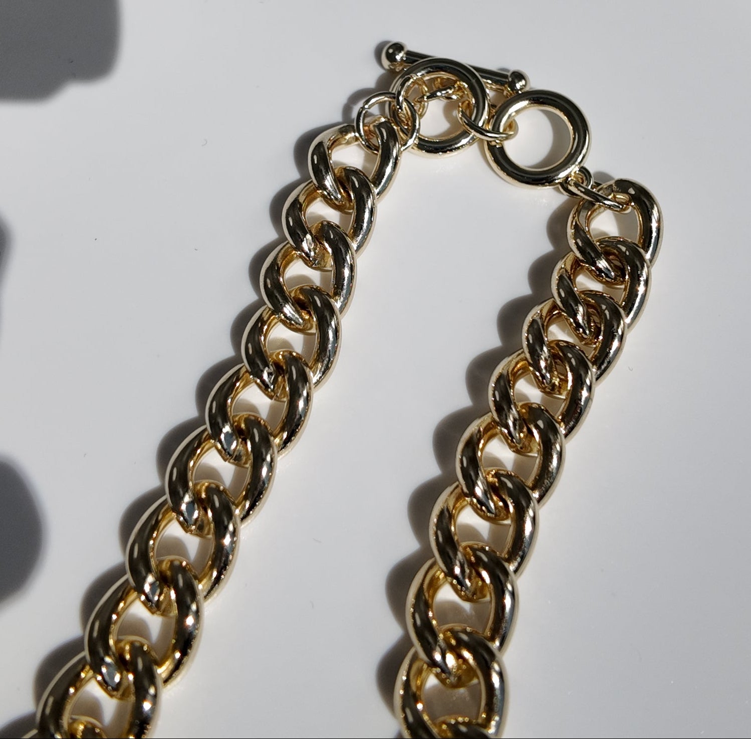 Close-up of polished gold chain links and clasp detail on the Colette Pavé Link Necklace