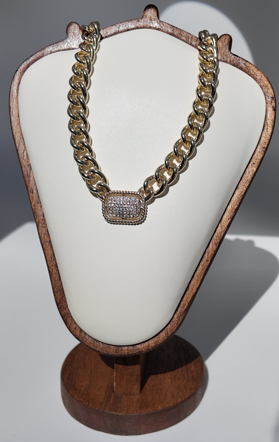 Colette Pavé Link Necklace displayed on jewelry stand featuring oversized polished gold links and pavé centerpiece