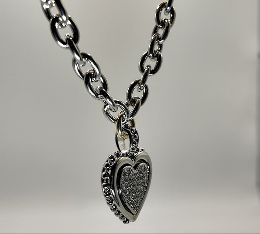 Silver chain necklace with a heart-shaped pendant on a light gray background