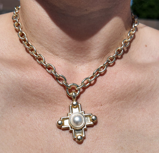 Model wearing the Evangeline Cross Necklace featuring a matte gold chain and pearl center cross pendant