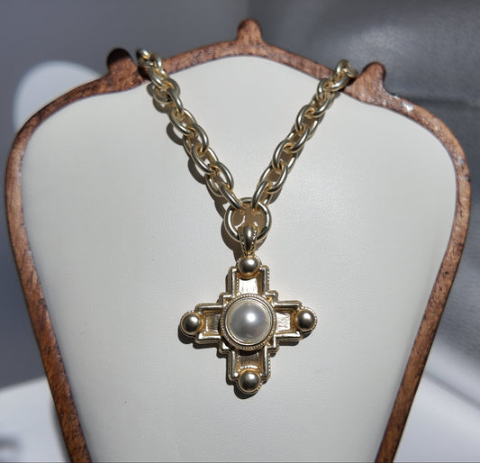 Evangeline Cross Necklace displayed on jewelry stand with matte gold chain and pearl cross pendant
