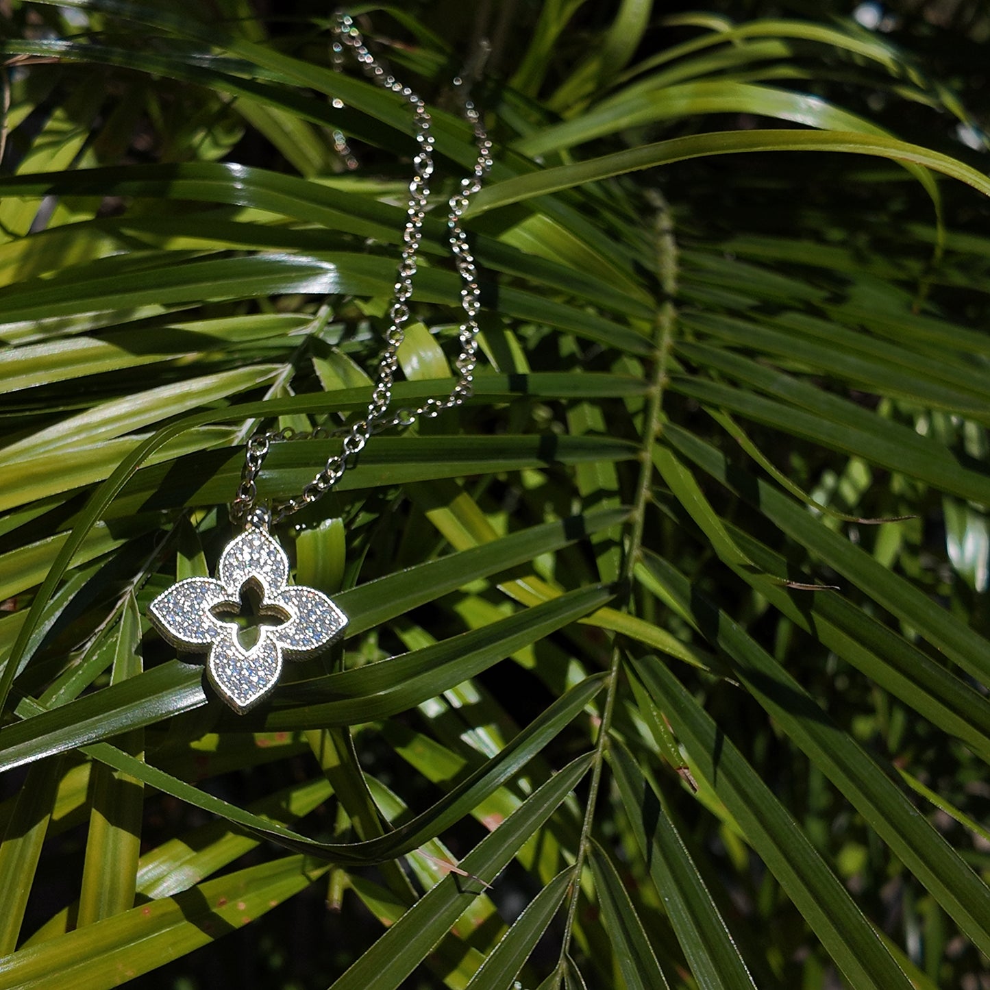 Juliette Open Motif Necklace styled on deep green tropical palms with luxury editorial aesthetic