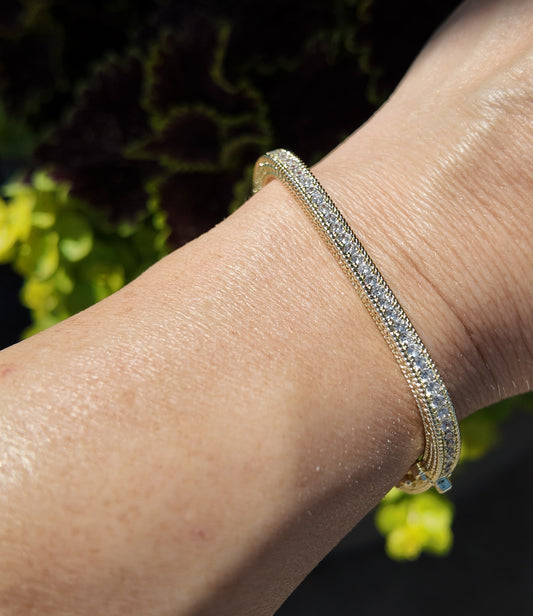     Close-up of Monaco gold tennis bangle bracelet with sparkling cubic zirconia detailing worn on wrist