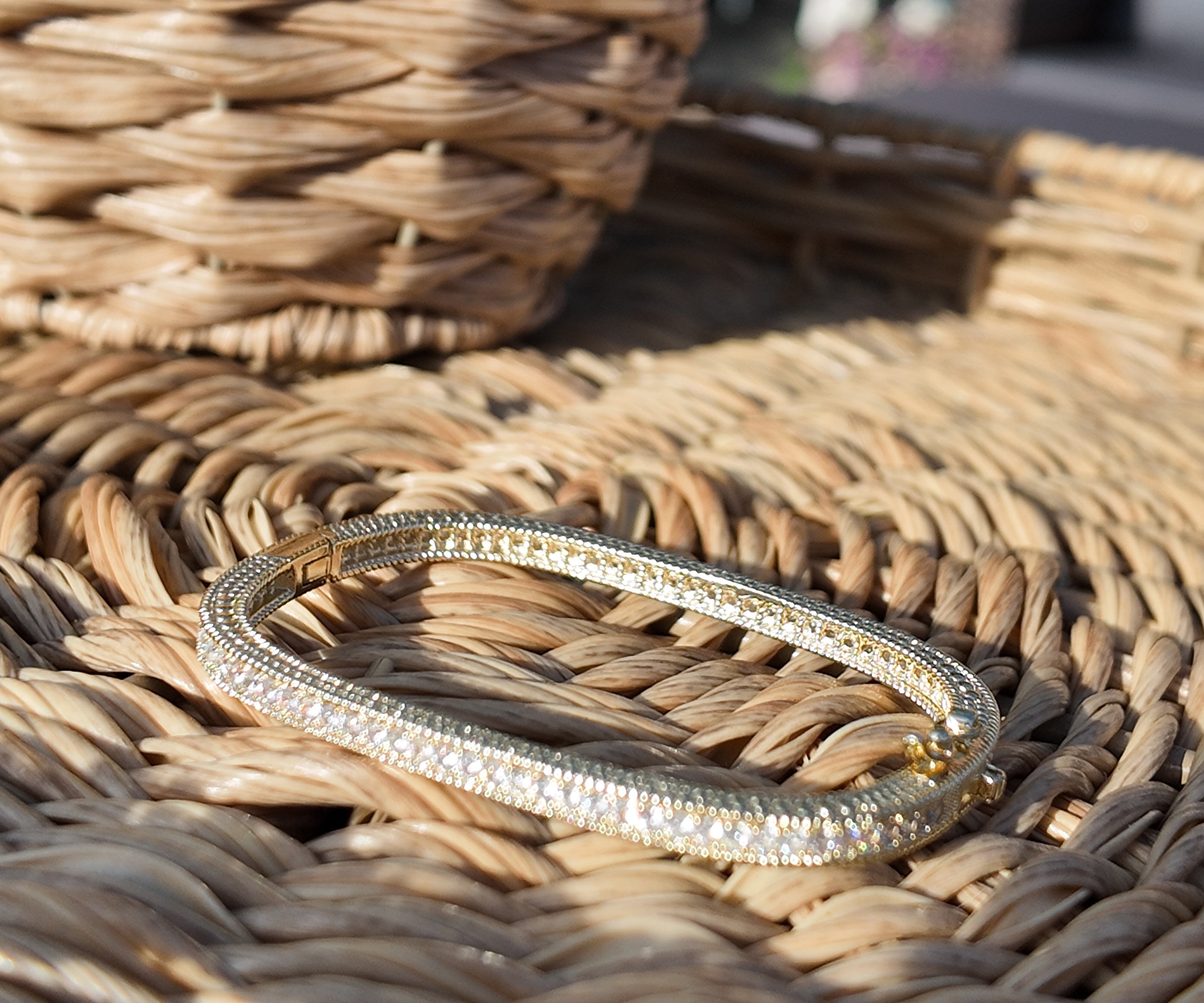 Gold bracelet with clear stones on a woven surface