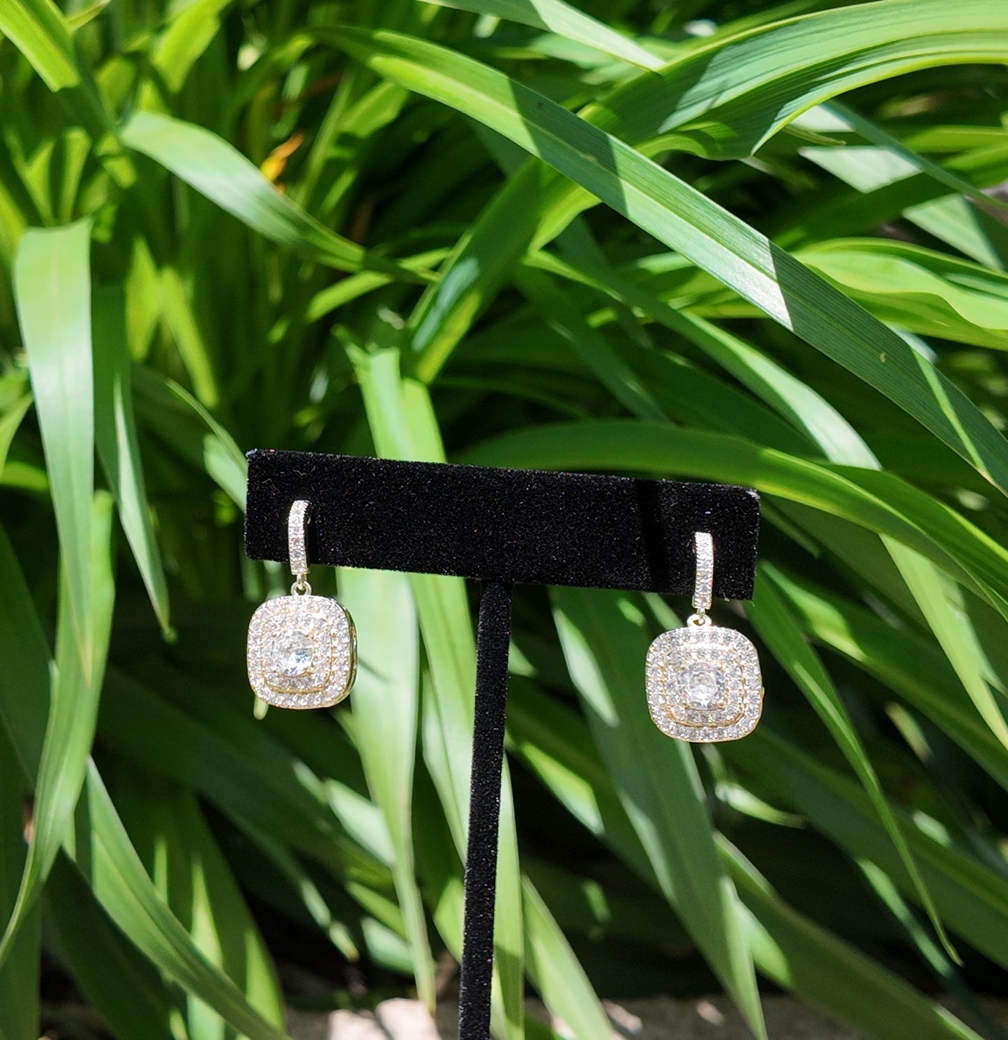 Gold pavé drop earrings styled against soft greenery outdoors