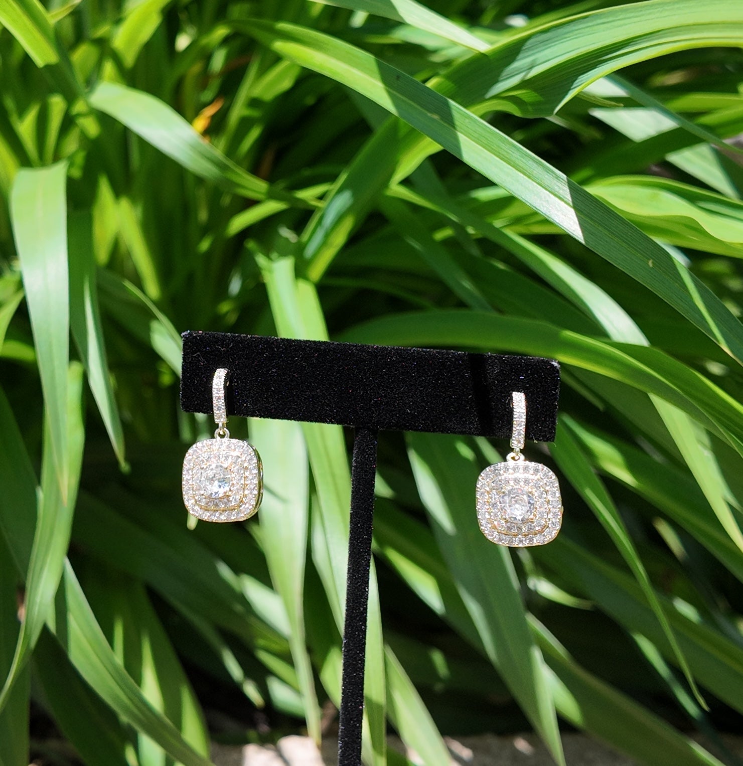 Gold pavé drop earrings styled against soft greenery outdoors
