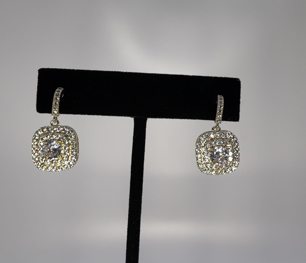 Elegant pavé drop earrings with crystal detailing on a jewelry stand