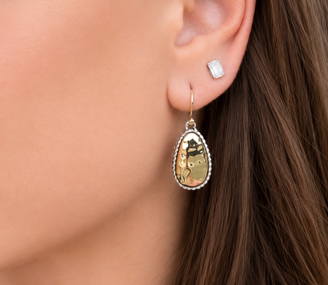 Close-up of two-tone teardrop earrings worn with soft neutral makeup
