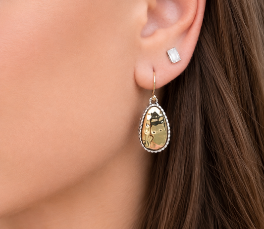 Close-up of two-tone teardrop earrings worn with soft neutral makeup